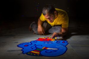 Young man making Rangoli on the occasion of Diwali